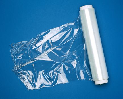 big roll of wound white transparent film for wrapping food, dark blue background, top view