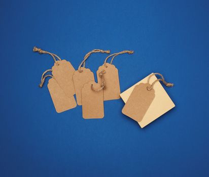 set of empty paper brown rectangular tags on a rope, price tags are on a blue trend background, top view