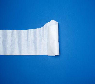 torn and twisted piece of white paper on a blue background, close up