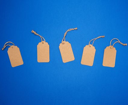 set of empty paper brown rectangular tags on a rope, price tags are on a blue trend background, top view