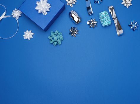cardboard gift square boxes, bows, ribbons for packaging on a dark blue background, empty space in the middle, trend colors