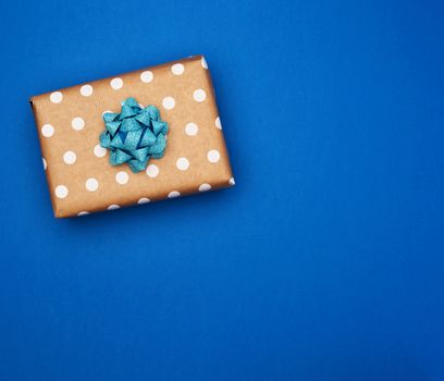 square brown box with white bow on a blue background, top view, empty place for an inscription