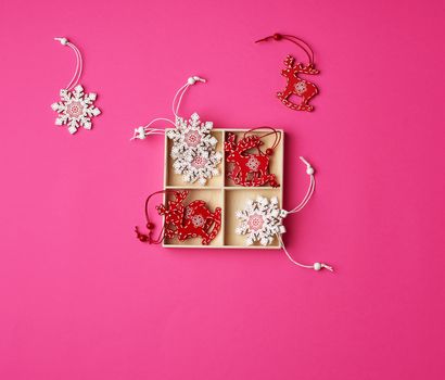 wooden carved Christmas decorations for the holiday tree on a pink background, flat lay