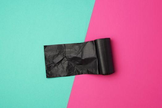 twisted roll with black garbage bags on a colored background, flat lay