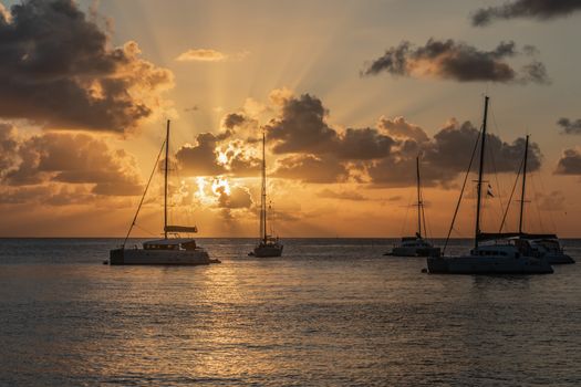 Sunset view of yachts and catamarans anchored in the lagoon, Britannia bay, Mustique island, Saint Vincent and the Grenadines, Caribbean sea