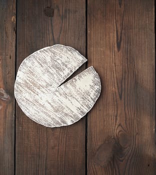 round white cutting board on a brown wooden background, top view