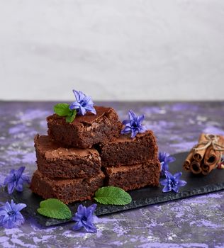 stack of square pieces of brownie pie on a black graphite plate, top view