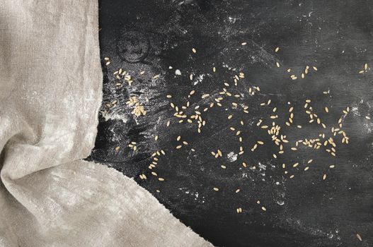 black background, near a gray linen towel, top view, sprinkled with flour and wheat, copy space