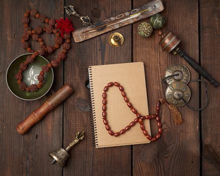 Copper singing bowl, prayer beads, prayer drum and other Tibetan religious objects for meditation and alternative medicine on a brown wooden background