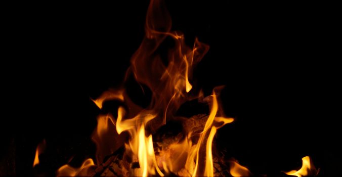bright orange and yellow flames with sparks on black background, close up