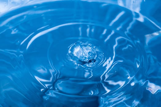 Water ripple background. Splashes from a drop of water. Raindrops on a blue background. The texture of the water. Aqua, turquoise, macro