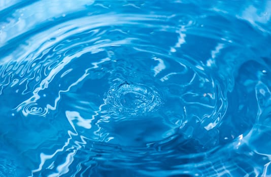 Water ripple background. Splashes from a drop of water. Raindrops on a blue background. The texture of the water. Aqua, turquoise, macro