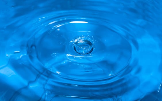 Splashes from a drop of water. Rain drops on a blue background. The texture of the water. Aqua, ripple, turquoise, macro