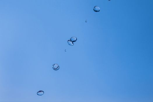 Water bubbles in the blue sky. Water drops on blue background. Aqua, rain, weather, clear. Life, freedom, ease.