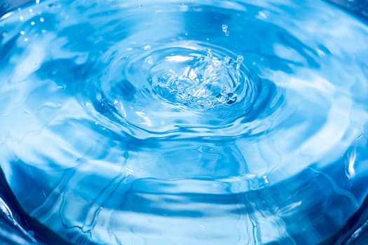 Splashes from a drop of water. Rain drops on a blue background. The texture of the water. Aqua, ripple, turquoise, macro
