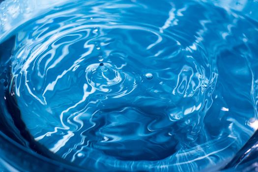 Water ripple background. Splashes from a drop of water. Raindrops on a blue background. The texture of the water. Aqua, turquoise, macro