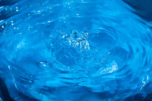 Splashes from a drop of water. Rain drops on a blue background. The texture of the water. Aqua, ripple, turquoise, macro
