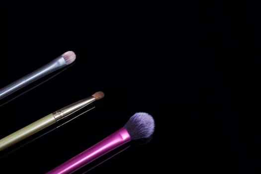 Makeup brushes on black background. Cosmetics, fashion, beauty, glamour. Accessories for make-up artist.