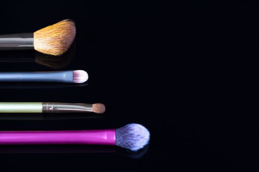 Makeup brushes on black background. Cosmetics, fashion, beauty, glamour. Accessories for make-up artist.