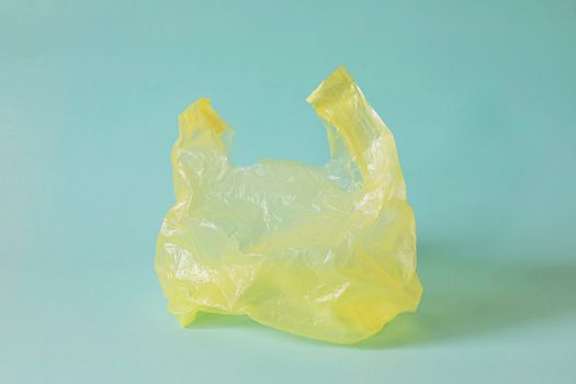 Empty yellow plastic bag against light blue background for waste recycling concept