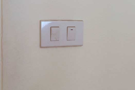 White electrical switch plate on the wall for control the light turning on or off. 