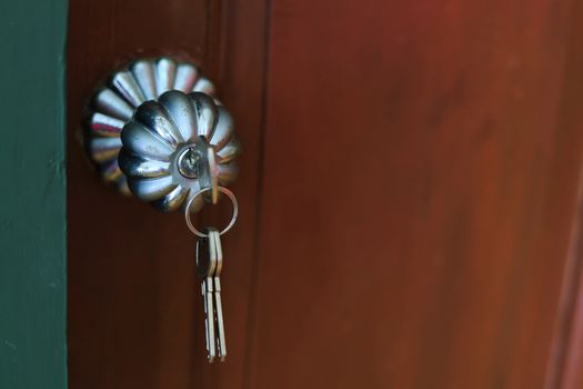 Close up of door knob with key  on wooden door for unlock to enter the room.