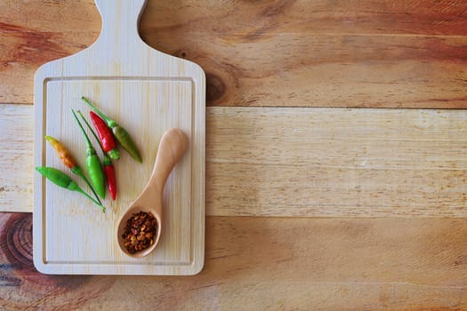 A spoon of cayenne pepper and fresh chilli on wooden background for food ingredients and cooking concept