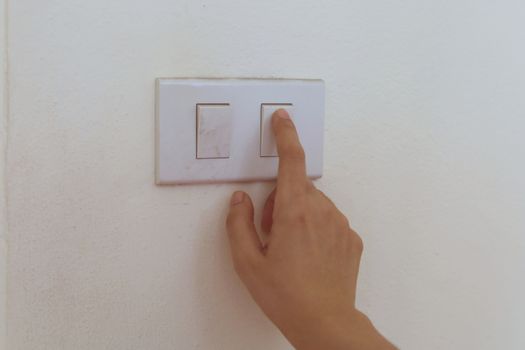 Hand pressing the button to turn the light on or off for saving energy cost concept.