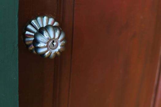 Close up of door knob on wooden door for handle to enter or exit the room.