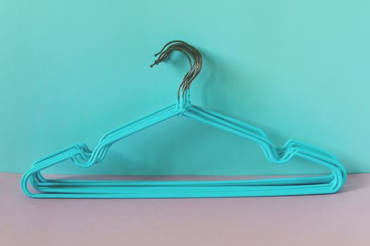 Clothes hangers on blue-pink background for household items.