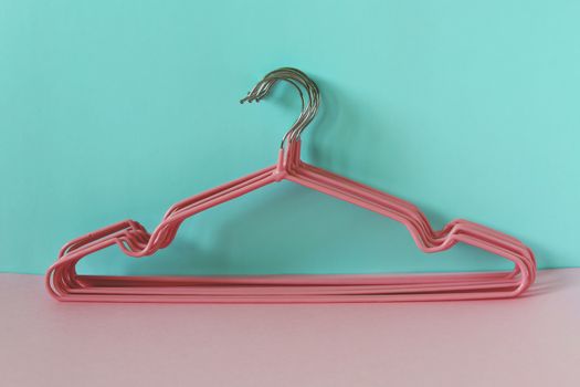 Clothes hangers on blue-pink background for household items.