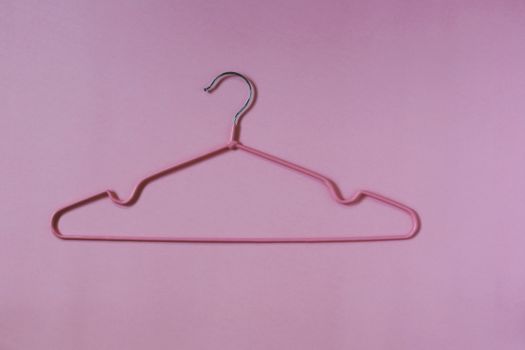 Clothes hangers on pink background for household items.