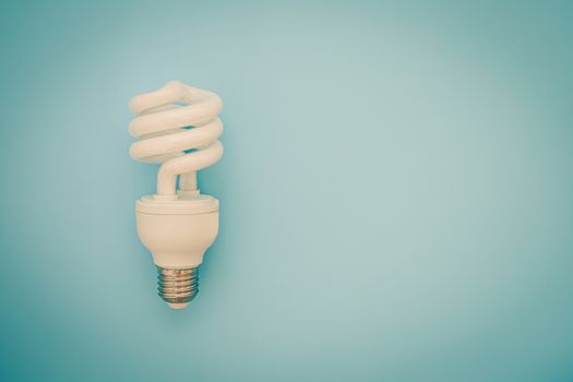 Fluorescent light bulb on blue background for energy savings concept