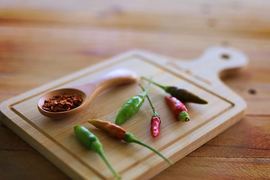 A spoon of cayenne pepper and fresh chilli on wooden background for food ingredients and cooking concept