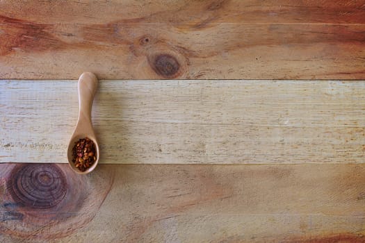 A spoon of cayenne pepper on wooden background for food ingredients and cooking concept