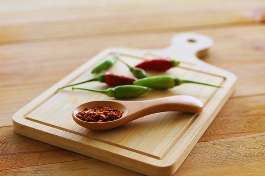 A spoon of cayenne pepper and fresh chilli on wooden background for food ingredients and cooking concept