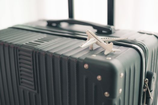 White airplane model on black luggage against blurred background for travel and journey concept