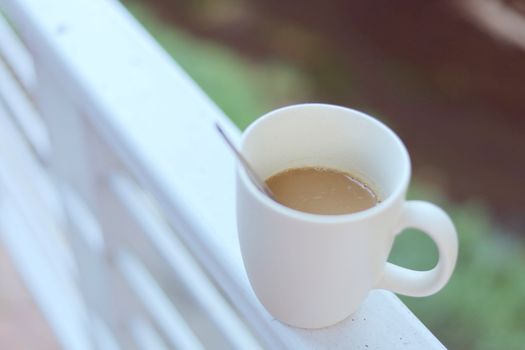 White coffee cup against blurred natural green background for drinks and beverage concept