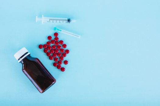Blood tonic includes multivitamins, folic acid, and iron liquid with bottle and syringe injection on blue background for healthcare and medical concept