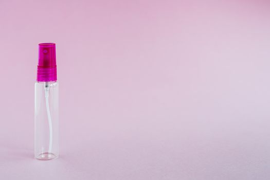 Transparent glass perfume and cosmetic spray bottle on pink background for product packaging concept