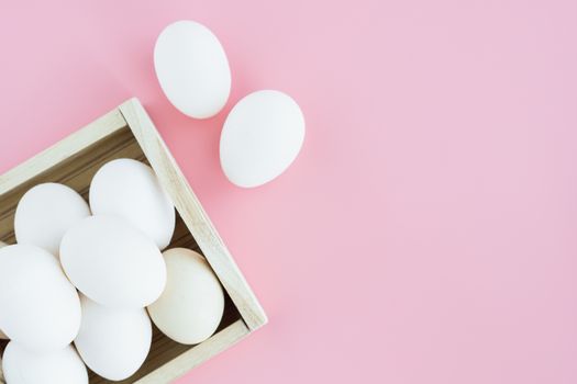 White eggs in the wooden tray on pink background for healthy food concept