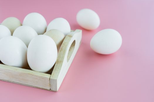White eggs in the wooden tray on pink background for healthy food concept
