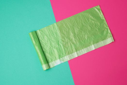 green transparent plastic bag for garbage on a colored background, top view