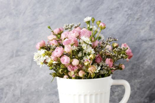 Mini pink rose flowers in white cup