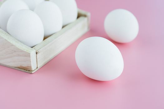 White eggs in the wooden tray on pink background for healthy food concept