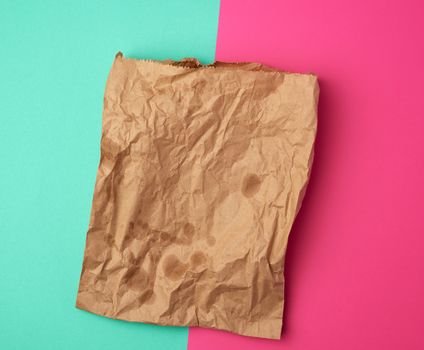 open brown paper bag for food packaging with greasy stains on a pink green background, concept of rejection of plastic bags to save the environment