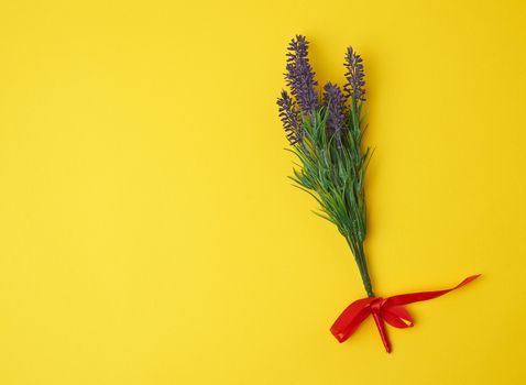 lavender bouquet and red ribbon on a yellow background, top view, copy space