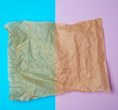 torn brown pieces of parchment paper on a blue purple background, flat lay, copy space