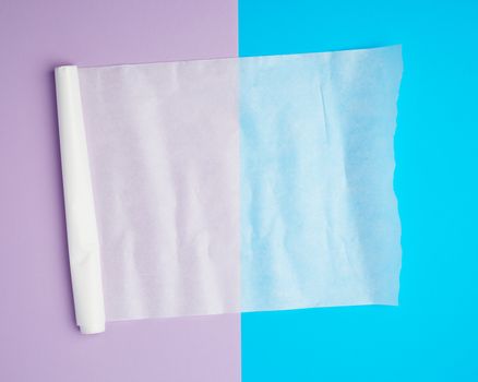 unwound white parchment baking paper on a blue purple background, top view