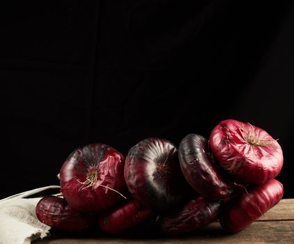 round red onion in husk on a gray linen napkin, black background, close up